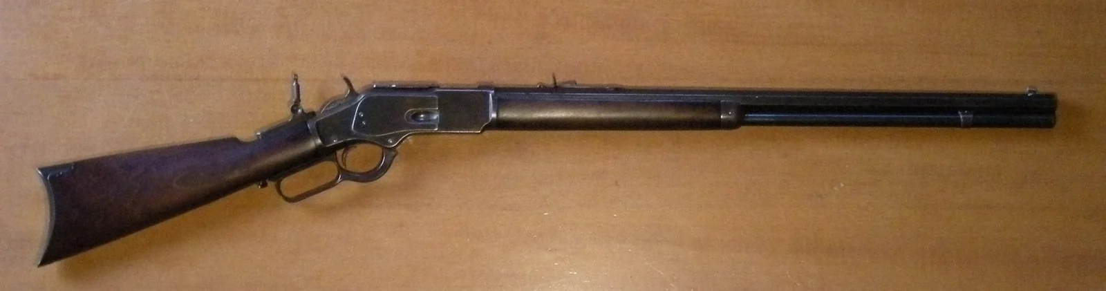Full side view of a Winchester Model 1873 with wooden stock and lever.